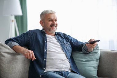 Mutlu sakallı son sınıf öğrencisi evde televizyon izliyor.