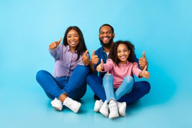 Mutlu siyahi aile, yere oturmuş el sallıyor.