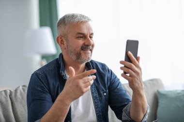 Mutlu kıdemli adam, akıllı telefon kullanarak görüntülü arama yapıyor.