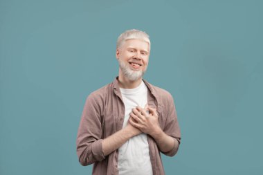 Samimi albino adam göğsünde el ele tutuşuyor. Minnettarlığını ve turkuaz stüdyo geçmişindeki olumlu duygularını dile getiriyor.