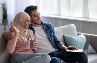 Mutlu adam ve kadın görüntülü konuşma yapıyorlar, laptop kullanıyorlar.