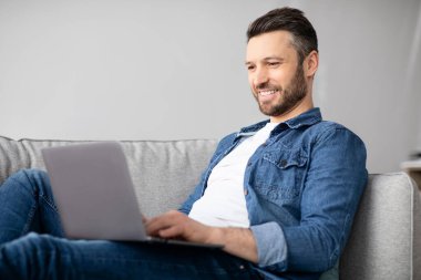 Gülümseyen adam dizüstü bilgisayar kullanıyor, yarı zamanlı çalışıyor.