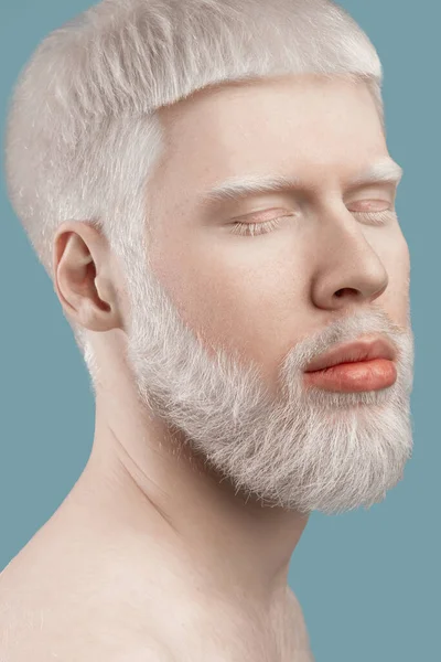 Albinisme concept. Headshot van de jonge albino man met gesloten ogen, bleke huid en wit haar poseren op studio achtergrond — Stockfoto