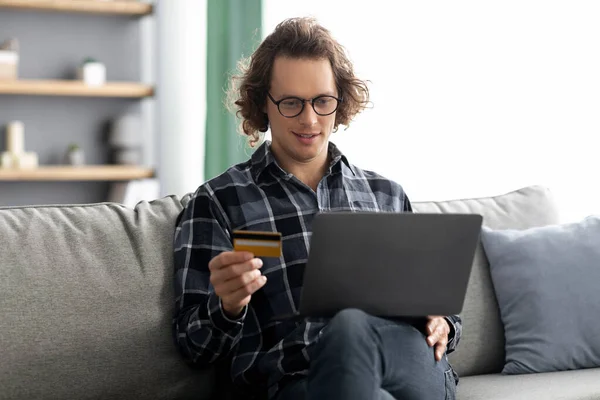 Guy χρησιμοποιώντας πιστωτική κάρτα και Laptop ψώνια σε απευθείας σύνδεση στο σπίτι — Φωτογραφία Αρχείου