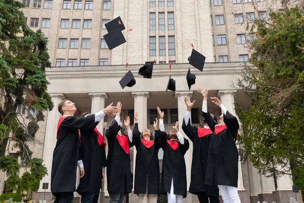 International group of students throwing graduation caps up