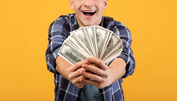 Nerozpoznatelný mladý muž držící fanoušky peněz, vyhrávat loterie na oranžovém pozadí studia, detailní záběr rukou — Stock fotografie