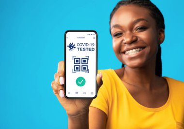 Siyah kadın covid-19 için immün dijital pasaportlu akıllı telefon gösteriyor.