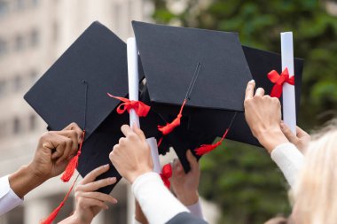 Mezuniyet şapkaları ve diplomaları öğrencilerin elinde, yakın plan.