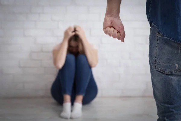 Huiselijk geweld, tirannie en slaan. Verschrikte vrouw bedekt haar hoofd met handen en zit op de vloer — Stockfoto