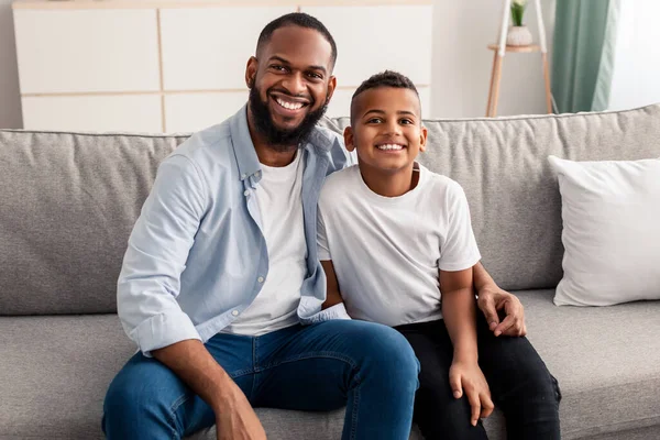 Ritratto di padre e figlio nero che si abbracciano sul divano — Foto Stock