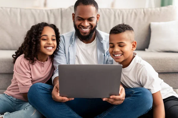 Happy Afrikaans amerikaanse familie met behulp van laptop in de woonkamer — Stockfoto