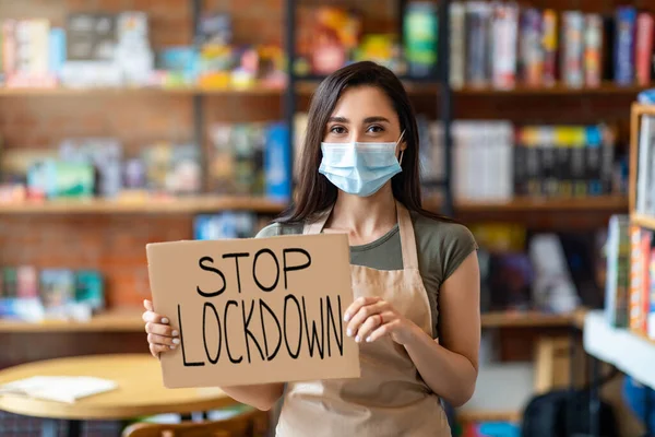 Joven dama con máscara protectora y mostrando pancarta parada de bloqueo, posando a la cámara en el interior de la cafetería — Foto de Stock