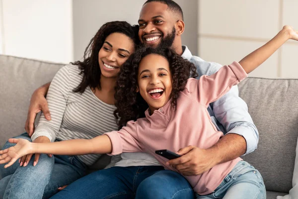 Feliz jovem família assistindo televisão sentado no sofá — Fotografia de Stock