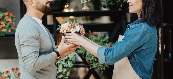 Çekici ve güler yüzlü bir müşteri marketten bir buket taze çiçek alıyor.