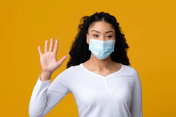 在结肠病毒传播过程中。戴医疗面具的黑人女士在相机前挥手 — 图库照片