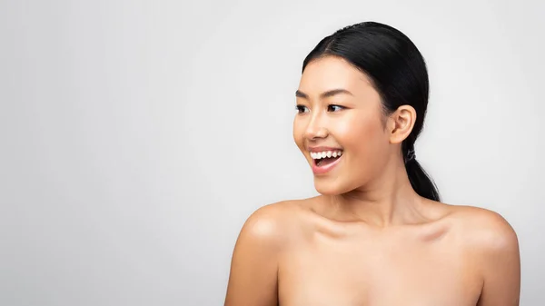 Fröhliche junge Japanerin lächelt vor grauem Hintergrund — Stockfoto