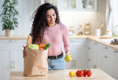 Alışveriş yaptıktan sonra markette paketleri boşaltan mutlu genç ev hanımı.