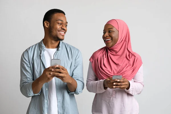 Щасливий мусульманський чоловік і жінка, використовуючи мобільні телефони — стокове фото