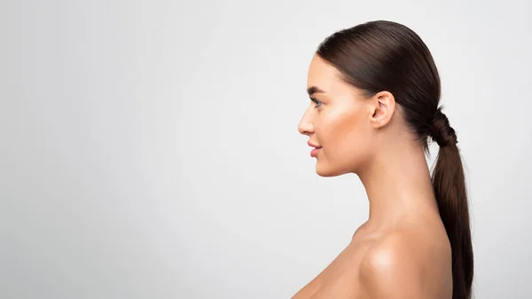 Vue de côté portrait de jeune femme sans chemise regardant à l'extérieur, fond gris — Photo