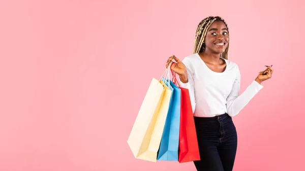 Zwarte dame met boodschappentassen bij roze studiowand — Stockfoto