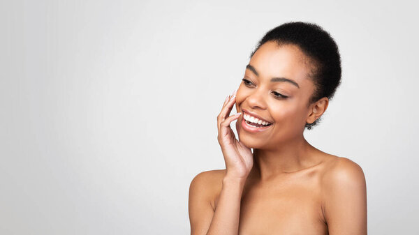 African American Woman Smiling Touching Face Looking Aside, Gray Background