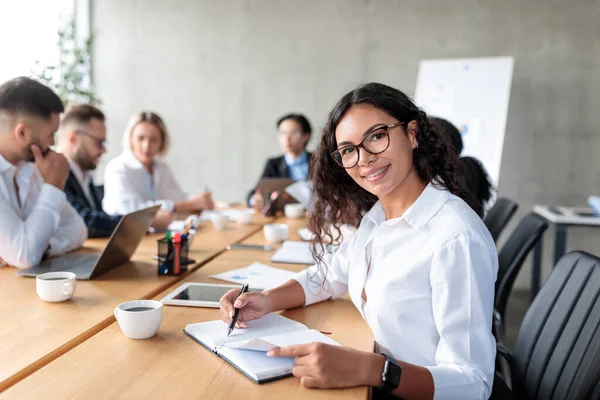 Femme d'affaires prenant des notes souriant à la caméra lors de la réunion d'entreprise Intérieur — Photo