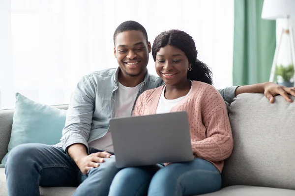 Happy african american family sitting on couch, using laptop — Stock Photo, Image