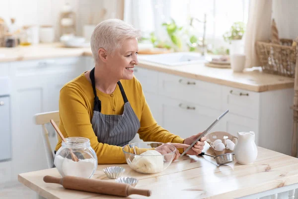 Glückliche alte Frau kocht nach Rezepten aus dem Internet — Stockfoto