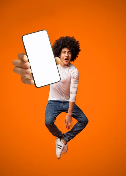재미있는 젊은 흑인 청년 이 생방송으로 오렌지 스튜디오 배경 화면에 흰색빈 화면을 핸드폰에 보여 주며, 흉내를 냈습니다. — 스톡 사진