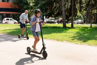 Mutlu çocuk ve babası e-scooter kullanıyor.