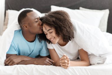 Hoş, sevimli, sevimli, gülümseyen, güzel çift, yatakta battaniyenin altında, hafta sonları boş vakitlerin tadını çıkarıyorlar.