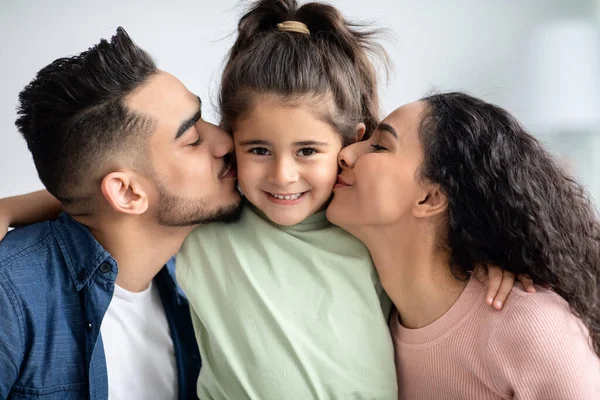 Glad barndom. Älskade arabiska föräldrar kysser sin lilla dotter i båda kinderna — Stockfoto