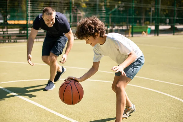 Papá deportivo enseñando a su hijo a jugar al baloncesto afuera — Foto de Stock