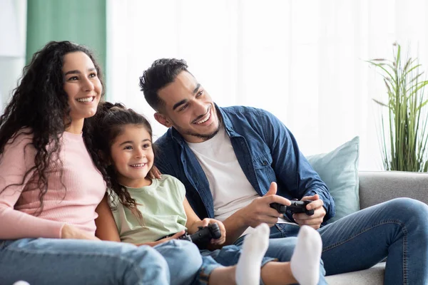 Familienzeit-Aktivitäten. Glückliche arabische Eltern spielen Videospiele mit ihrer kleinen Tochter — Stockfoto