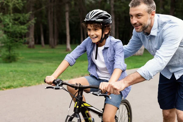 Boy learning how to ride bicycle with his happy dad — Stock Photo, Image