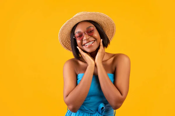 Portrait of gorgeous black woman in casual summer outfit touching her face and smiling at camera on orange background — Stock Photo, Image