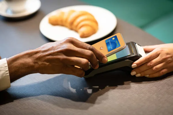 African american businessman paying with cellphone at cafe