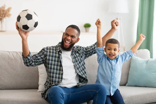 Fröhlich papa und sohn beobachten fußballspiel auf fernsehen indoor — Stockfoto