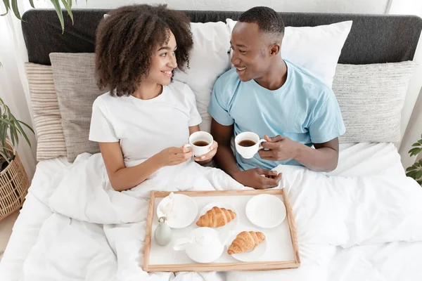 Belle matinée et couple romantique amoureux prendre le petit déjeuner au lit, se reposer et se détendre à la maison — Photo