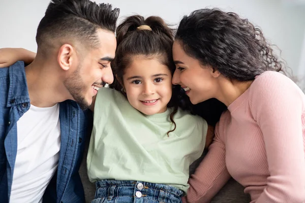 Föräldrakärlek. Glada arabiska föräldrar kela med sin söta lilla dotter hemma — Stockfoto