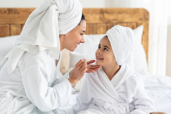 Mamá poniendo maquillaje en su pequeña hija linda —  Fotos de Stock