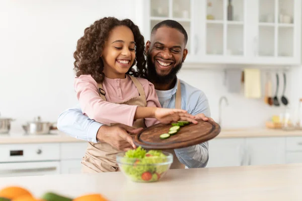 Neşeli afro baba ve kızı birlikte salata pişiriyorlar. — Stok fotoğraf