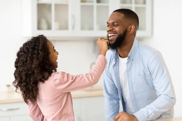 Afro-americana hija cocinar fresco ensalada alimentación papá — Foto de Stock