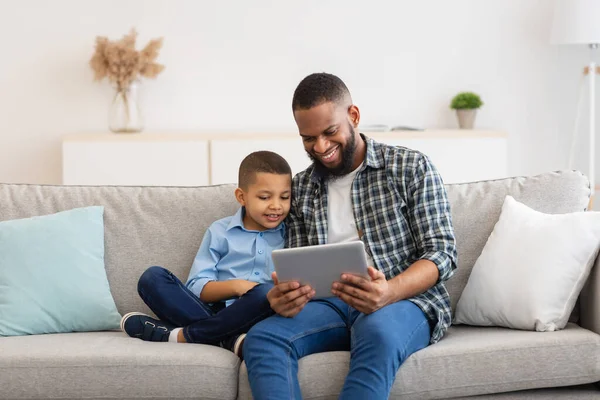 Ο μπαμπάς και ο γιος βλέποντας κινούμενα σχέδια σε απευθείας σύνδεση tablet στο σπίτι — Φωτογραφία Αρχείου