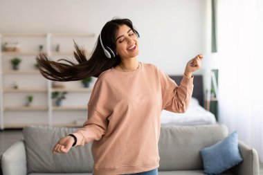 Dans eden ve kablosuz kulaklık takan genç bir kadın.