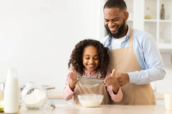 Cheerful afro man and his daughter preparing dough
