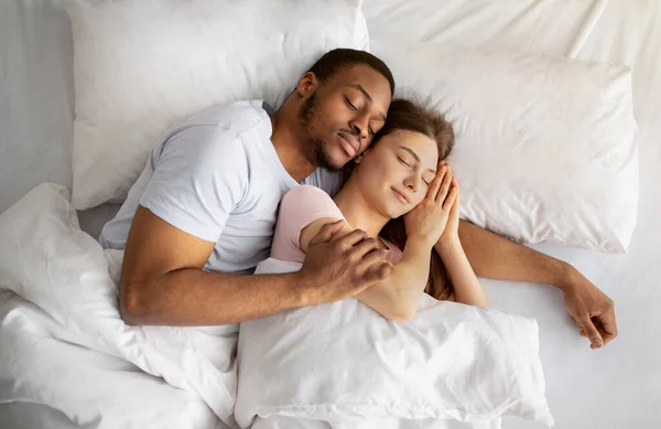 Iubind cuplul multirasial având dimineața confortabilă, îmbrățișându-se împreună în somn pe pat, vedere de sus — Fotografie, imagine de stoc