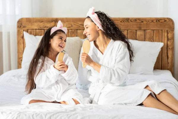 Madre e figlia divertenti con spazzole per capelli che cantano a casa — Foto Stock