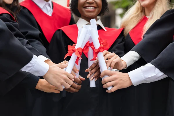 Cultivado de grupo multirracial de estudiantes uniendo sus diplomas juntos —  Fotos de Stock