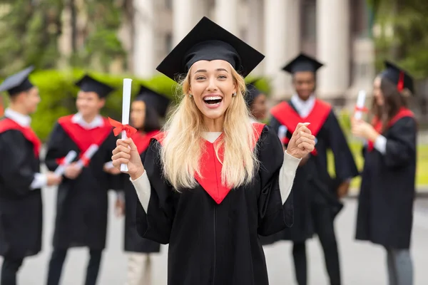 Känslomässig blond kvinna student som har examensfest — Stockfoto